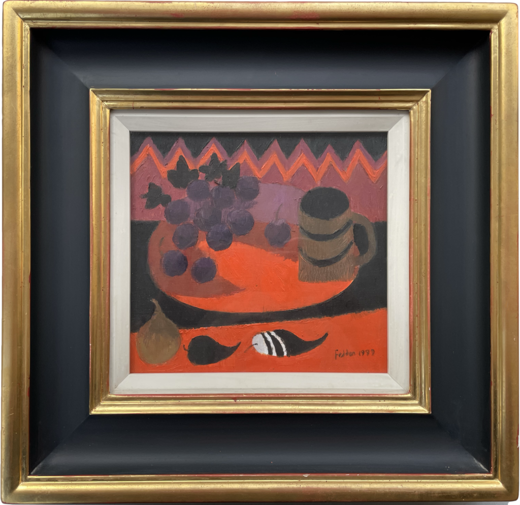 Mary Fedden oil painting of a table top still life with fruit and a mug, mainly painted in red and black, in a black and gilded frame